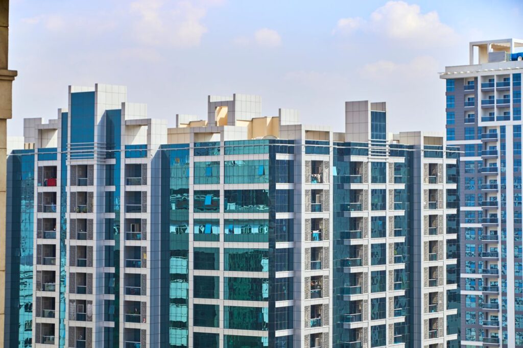 A cityscape view of modern high-rise buildings with reflective glass facades under a blue sky.